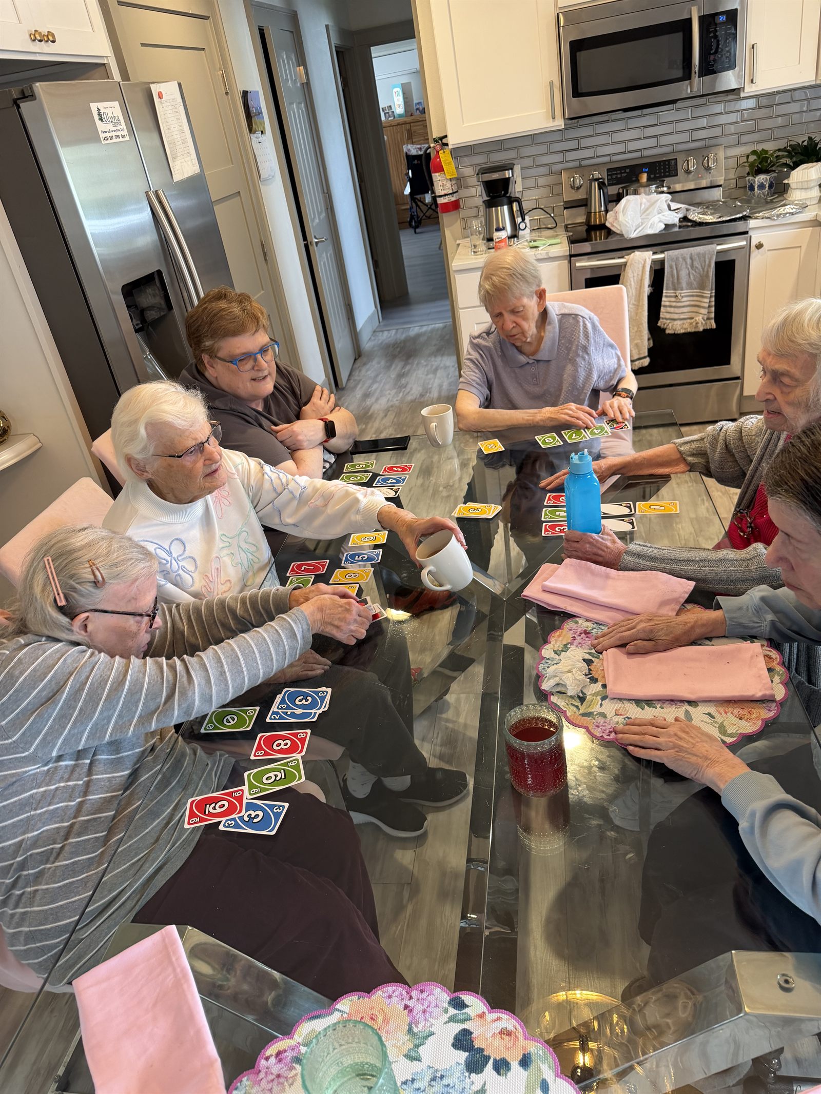 Six residents playing a card game together around the dining table