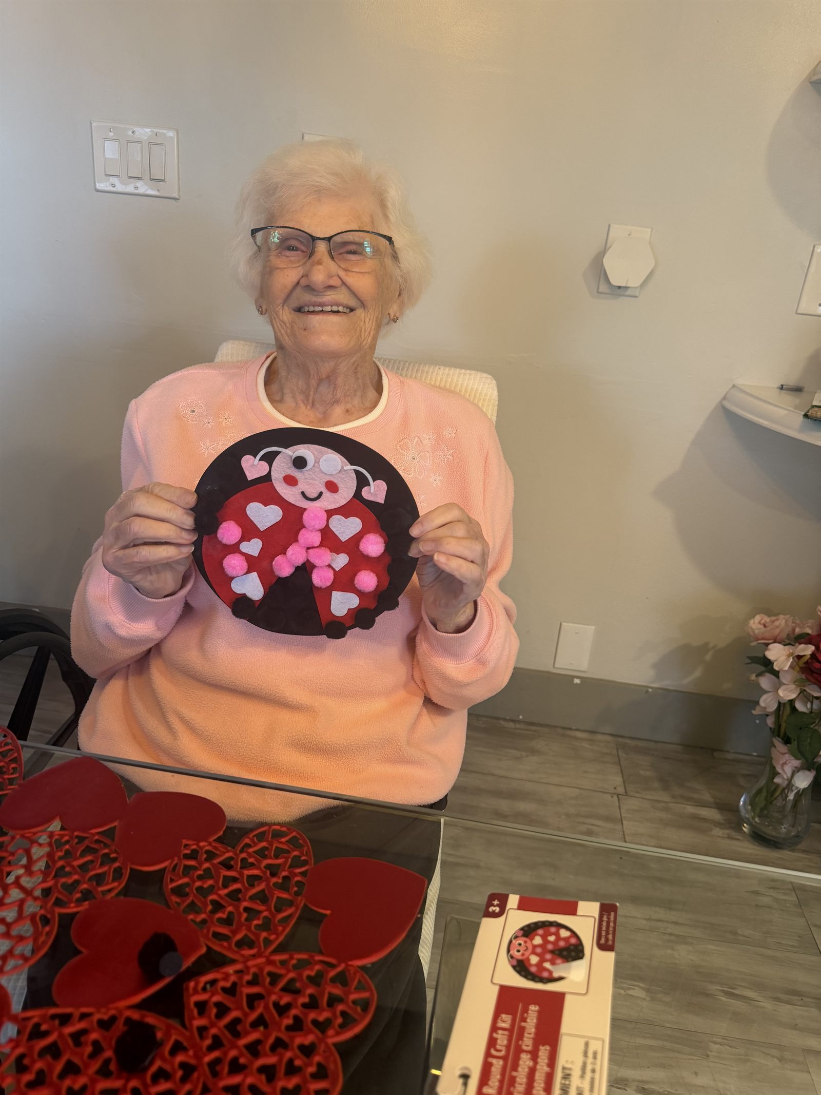 A resident holding up a felt ladybug craft she has just finished