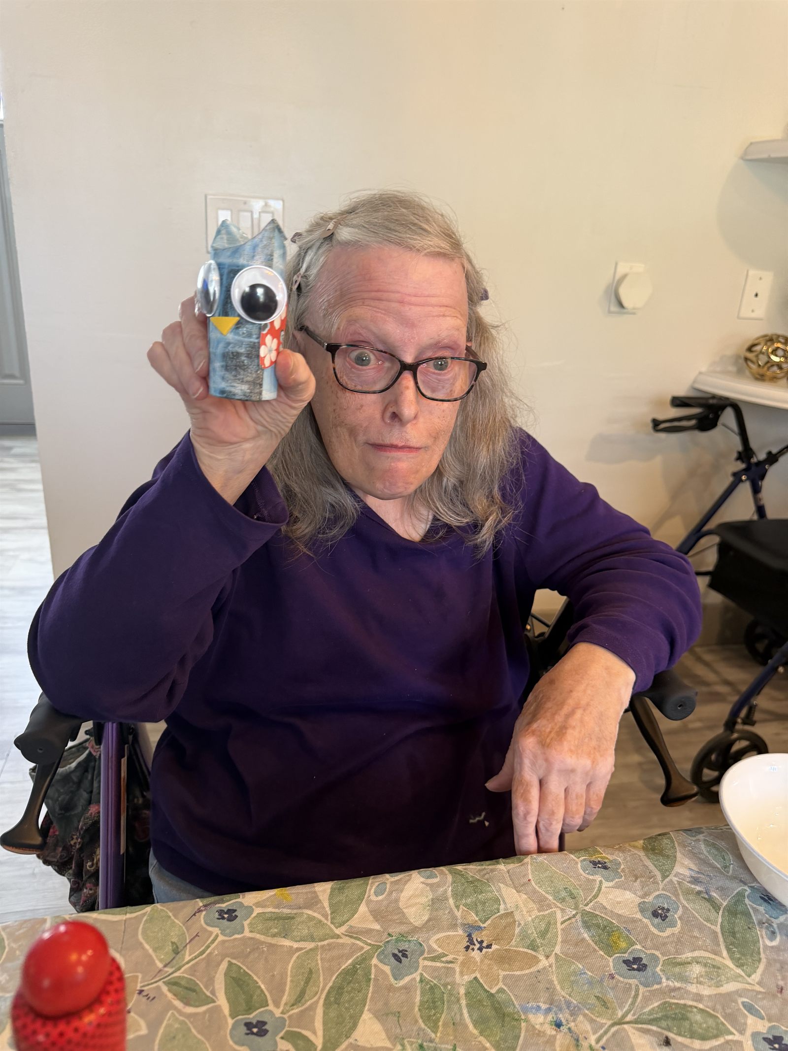 A resident holding a small paper owl craft she has made