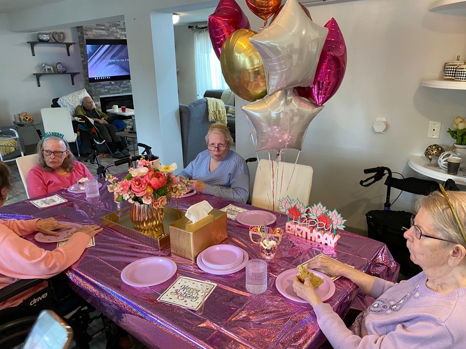 Residents around a table decorated in pink and gold for a birthday