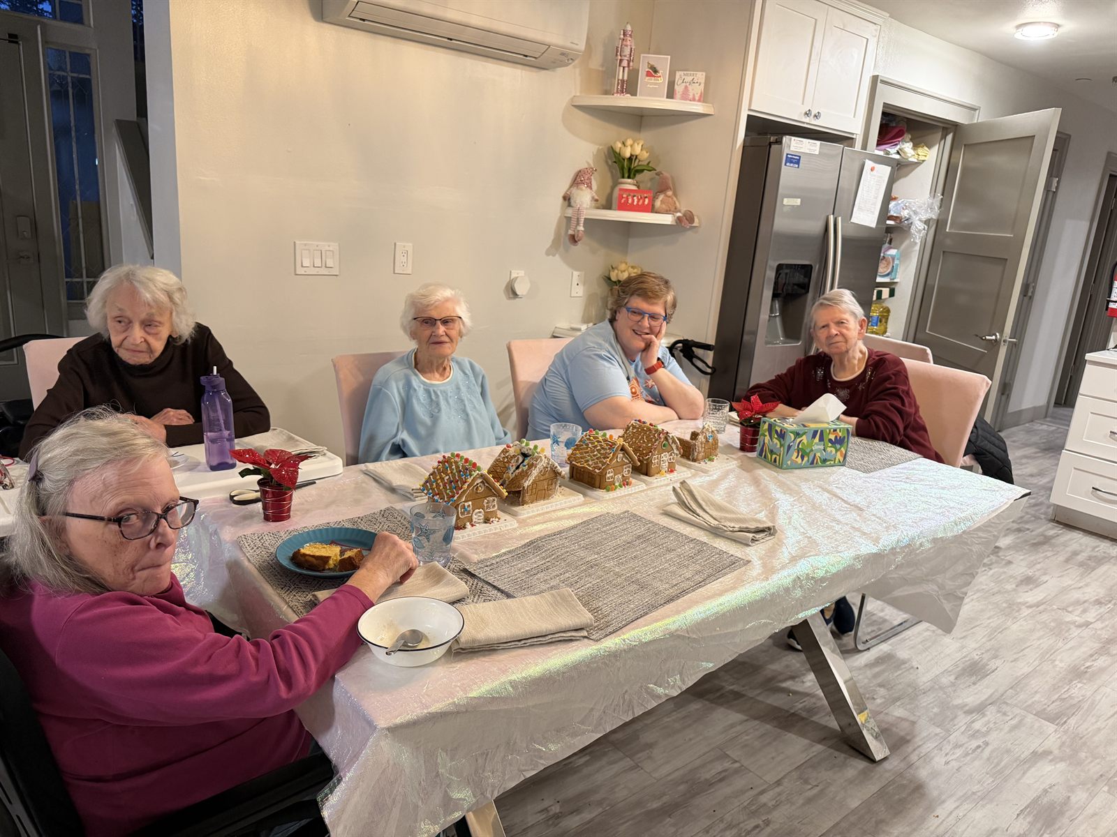 Residents around the table with a row of finished gingerbread houses