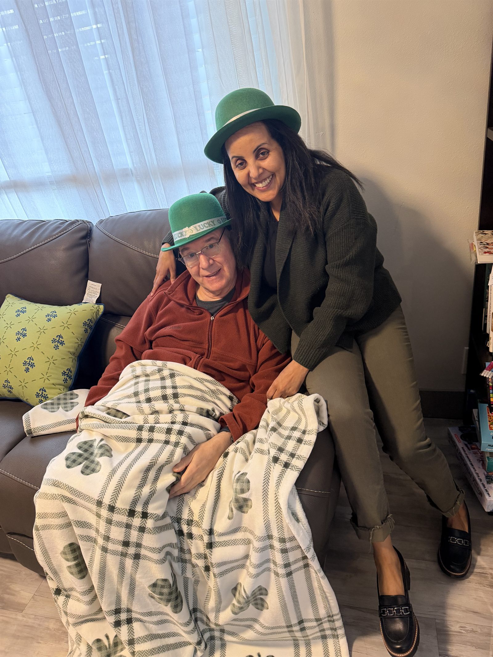 A resident and a caregiver wearing green hats