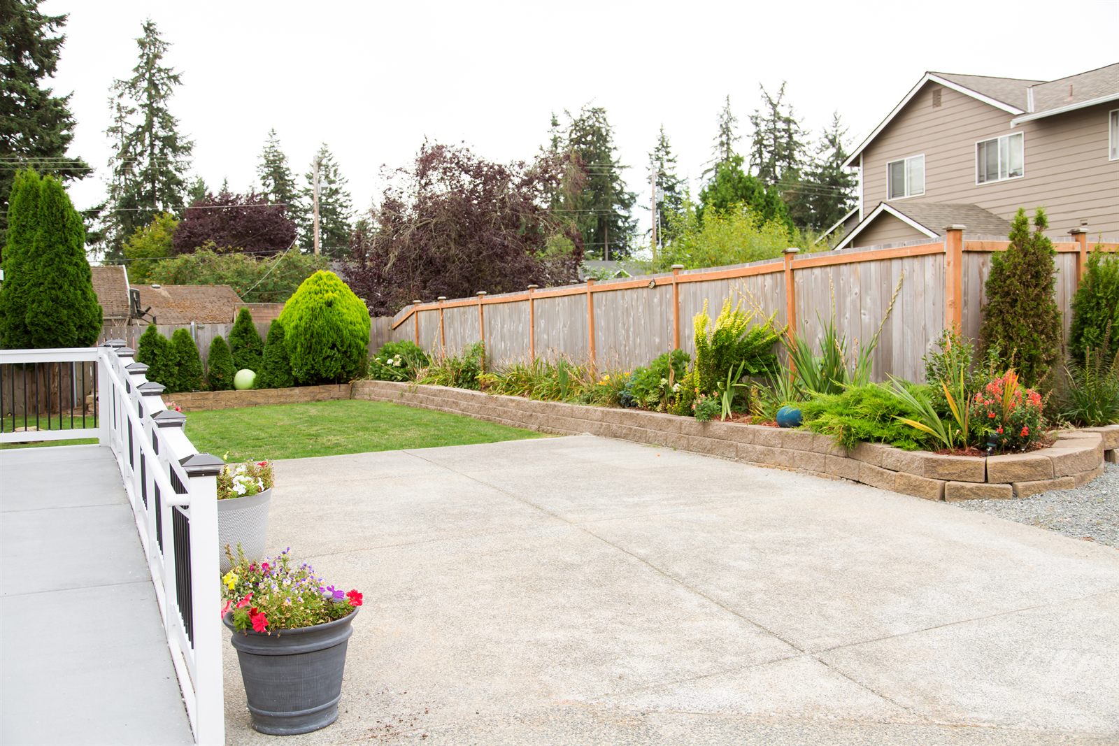 Fenced back garden with a lawn, flower beds and level paving
