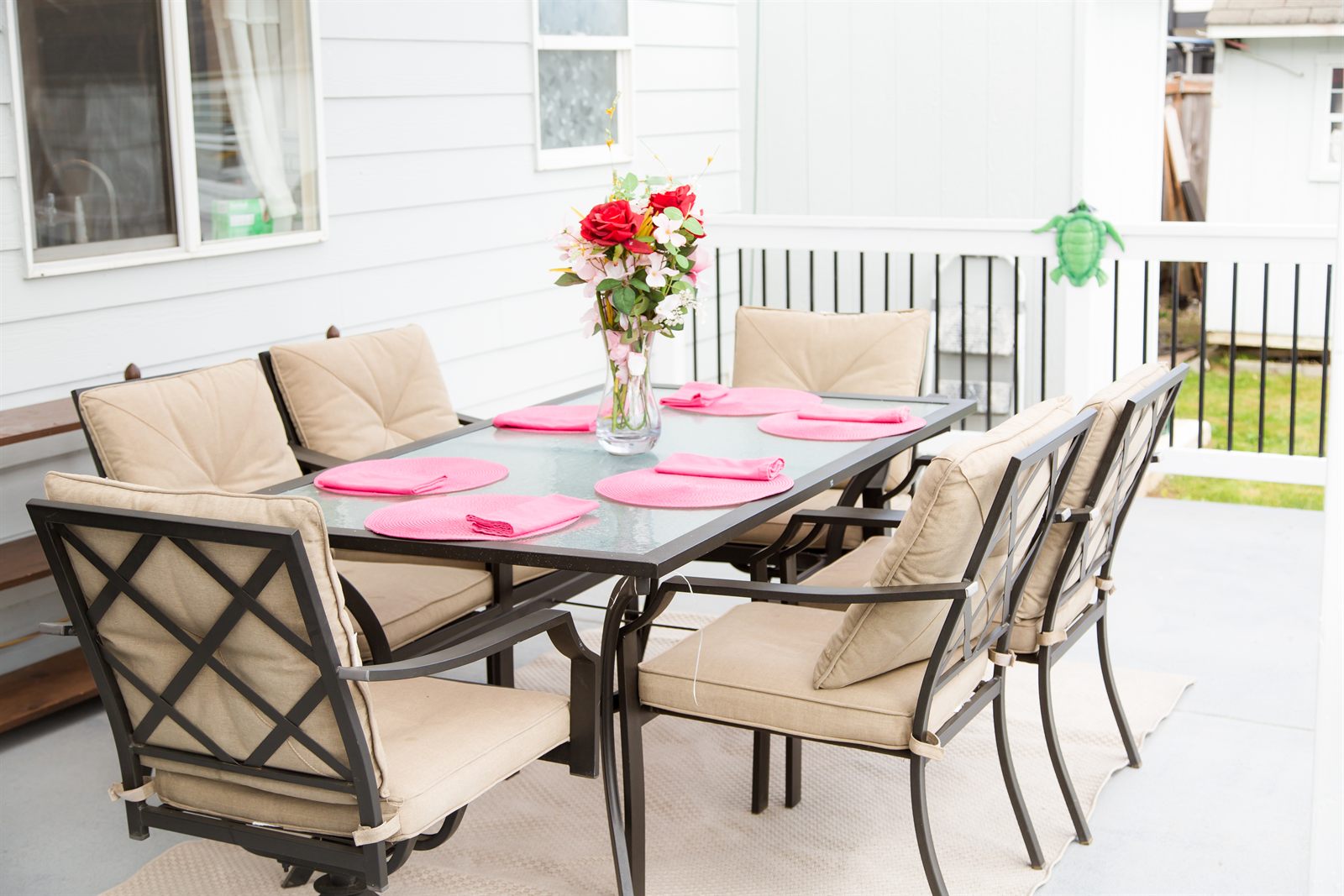 Outdoor patio table set with cushioned chairs and flowers