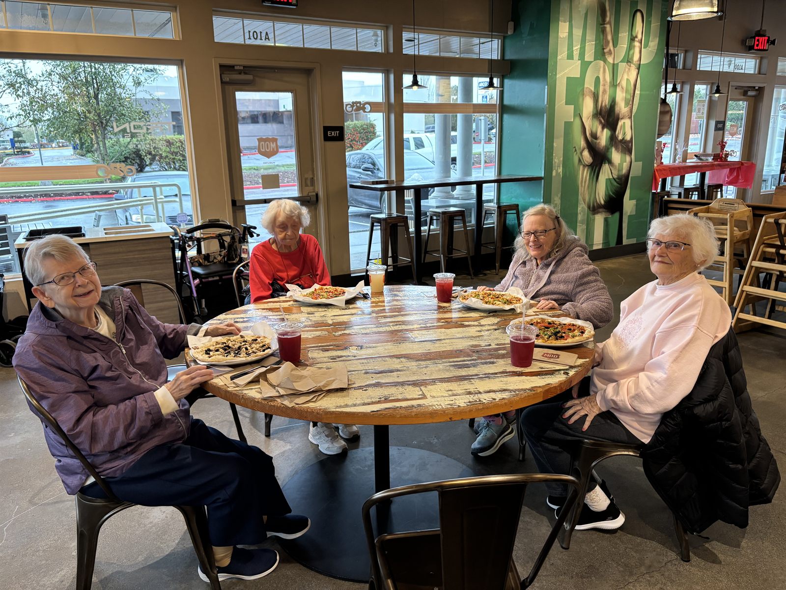 Four residents sharing pizza together at a restaurant
