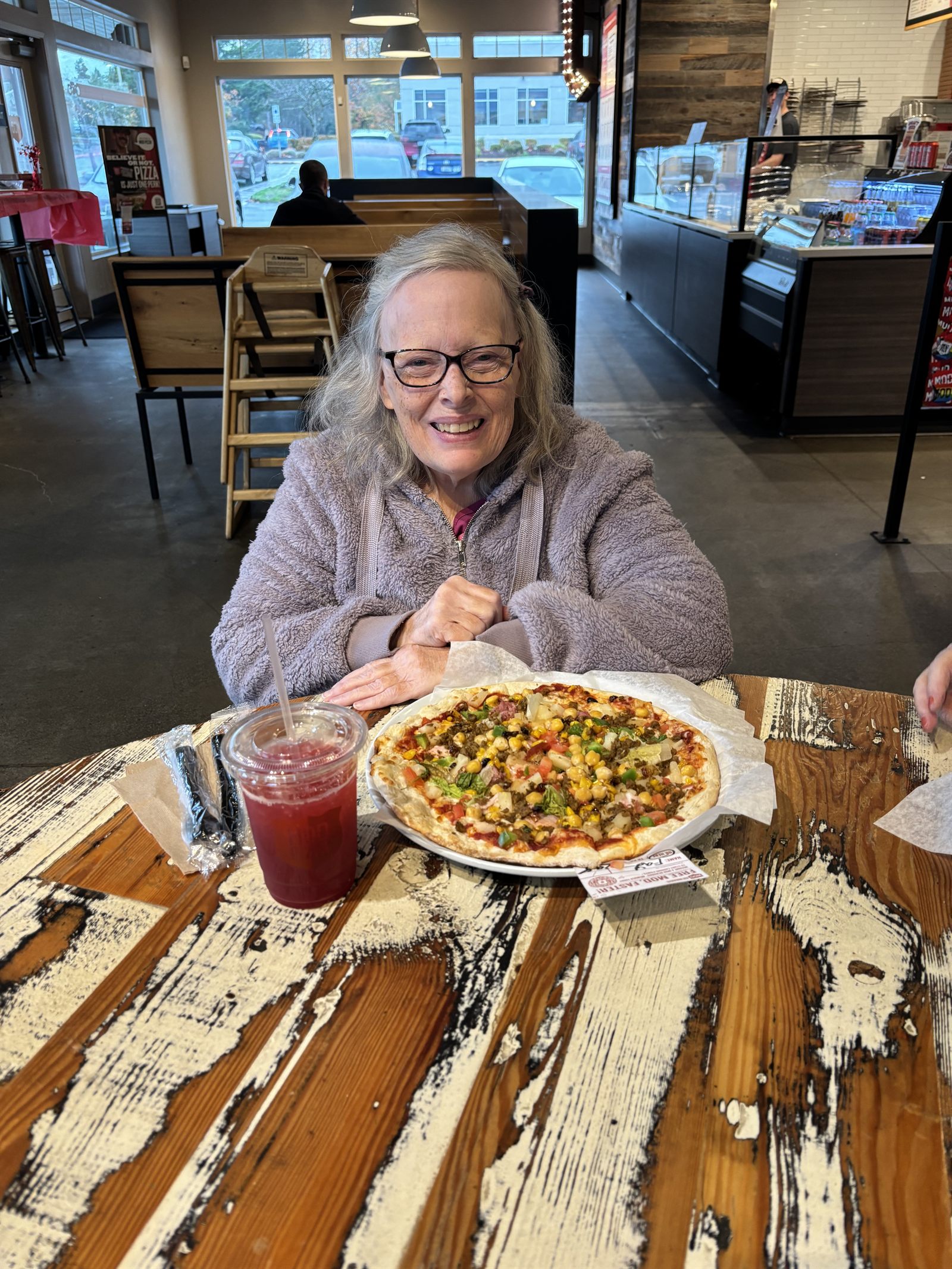 A resident with her own pizza at the restaurant table